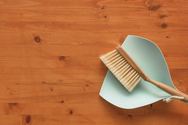 Dustpan and brush on wooden hardwood floor, flat lay top view