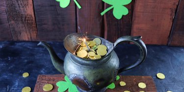 Patrick's Day, vintage pot with gold coins and burning sparklers, on a wooden background with shamrocks