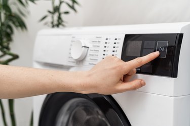 Woman washing laundry using modern automatic machine