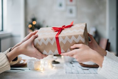 Woman giving her friend a wrapped Christmas gift