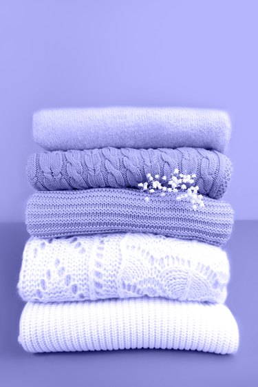 Stack of trendy violet and white knitted sweaters