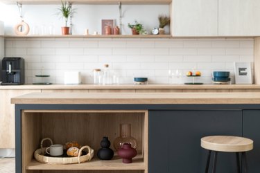 Open storage cabinet with vase, home decor and breakfast tray on shelf