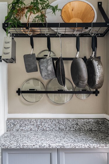 Pots, pans and skillets hanging on a rack in a kitchen