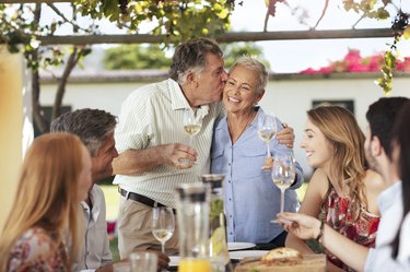 Happy senior couple with family having lunch together outside