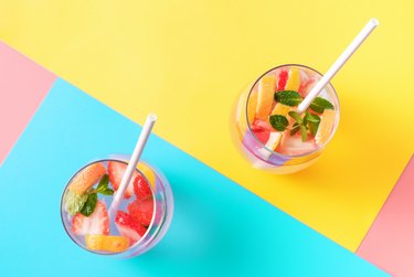 Two glasses with fruit iced tea drinks on colorful backgrounds top view.