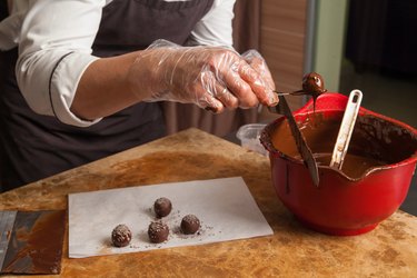 Crop pastry chef preparing candies