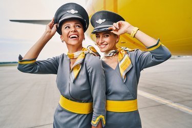 Joyous flight attendants in pilot caps at the airdrome