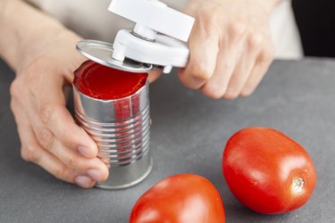 woman opening a can of tomatoes