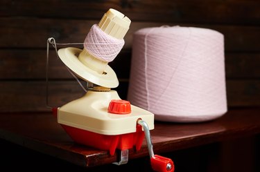 Mechanical yarn winder or reel while rewinding thread. Close-up, selective focus