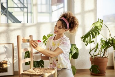 Young Woman Painting Chair At Home