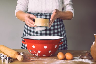 Woman sieving flour in domestic kitchen