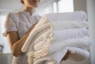 Woman holding stack of white towels