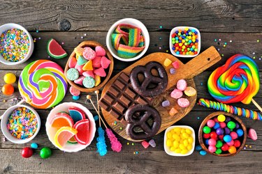 Colorful sweet candy buffet table scene, above view over rustic wood