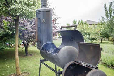 Smoker grill in home backyard, family patio, outdoor bbq party on open air, green garden background
