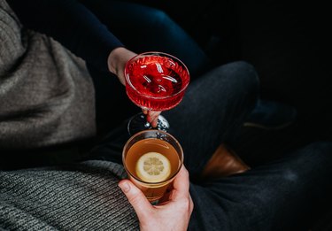 Top down image of two people sitting close to each other, holding festive cocktails