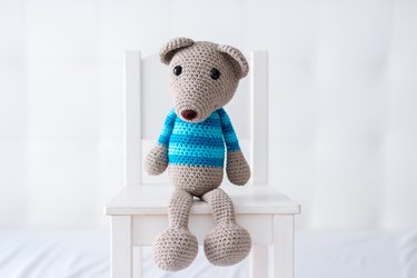 Handmade crocheted teddy bear with a striped shirt