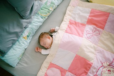 High Angle View Of Baby Boy Sleeping On Bed