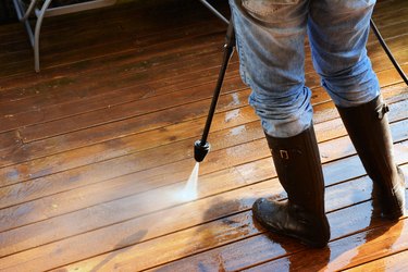 Woman using a high pressure washer on patio