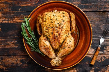 Delicious baked chicken on wooden table.  Dark background. Top view