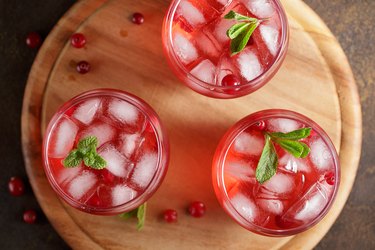 Three glasses with iced cranberry punch on wooden cutting board