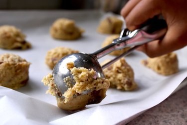 Hand scooping cookie dough on sheet
