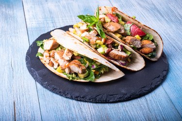 Mexican tacos with grilled chicken and vegetables on a slate plate close up