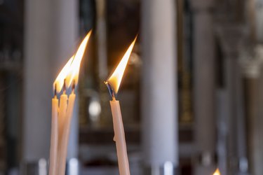 Four burning candles with flame inside of church