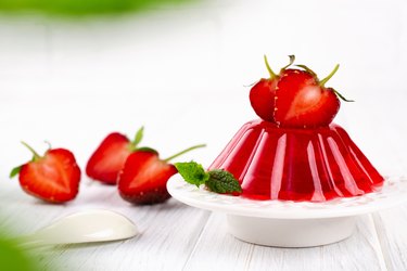 Strawberry jelly on white plate. Summer dessert with fruit jelly and fresh strawberry.