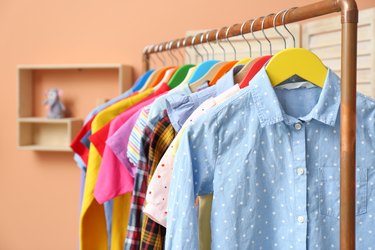 Different child's clothes hanging on rack indoors, closeup