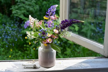 Bouquet of wildflowers in a vase on a wooden window sill.