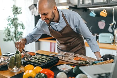 Young man roasting salmon steaks and asparagus on an electric grill