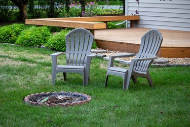 Pair of lawn chairs in a back yard with light shade, around an extinguished fire pit