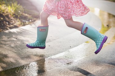 Waist-down view of girl jumping puddles in rain