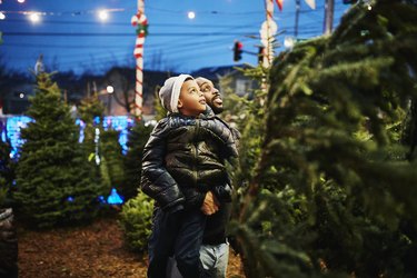 Father lifting up son while shopping for Christmas trees