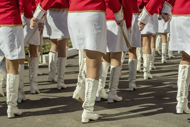 A group of girls in bright ceremonial costumes are marching along the city streets.