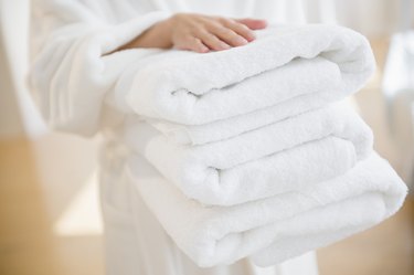 Woman carrying stack of clean towels