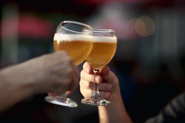 Two people toasting with IPAs in craft beer glasses