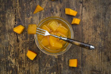 Glass of sweet-and-sour pickled pumpkin on dark wood