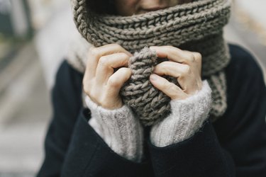 Woman's hands holding knitted scarf