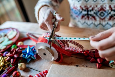 Close-up of hands cutting ribbon to wrap gifts