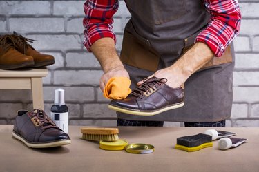 Man shining shoes with a rag in workshop. Small business. The process of cleaning shoes.