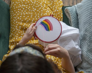 Directly above viewpoint of a lady embroidering a gay pride rainbow in support of LGBTQI+ Pride at Home.