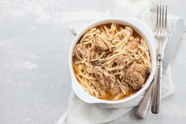 spaghetti with chicken in white bowl on ceramic background