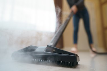 Woman washes the floor with a steam mop.