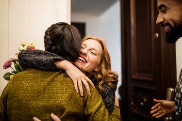 Woman embracing friend during visit for dinner party