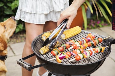 Hand turning over food on barbecue