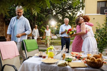 Girlfriends embracing when meeting for a dinner party in the back yard