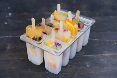 Homemade orange and lemon popsicles with edible flowers