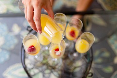 Woman pouring mimosa into glasses