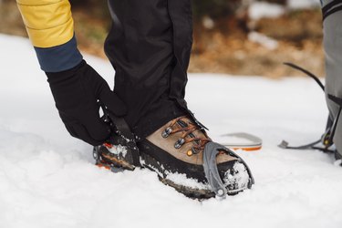 Man putting on crampons in the snow